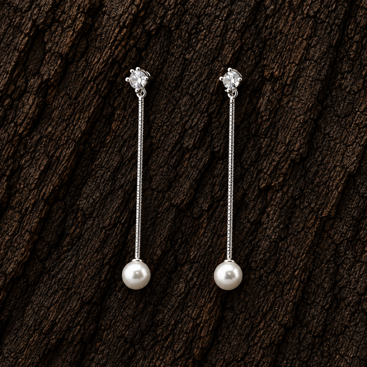 925 sterling silver CZ and white pearl long dangle earrings displayed on dark wood background.