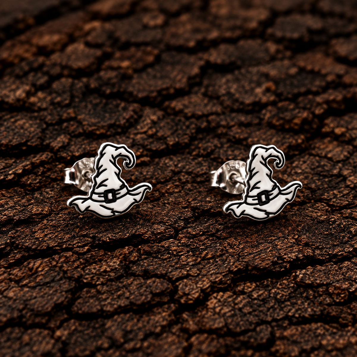 Sterling silver witch hat earrings displayed on dark bark background.