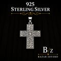 Silver cross pendant with intricate scrollwork engraving, crafted in 925 sterling silver and displayed against a dark elegant background.
