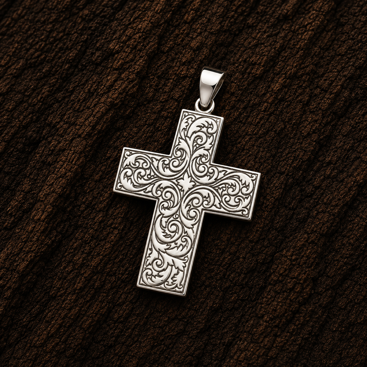 925 sterling silver cross pendant with detailed scrollwork engraving, shown close-up against a dark wood background.