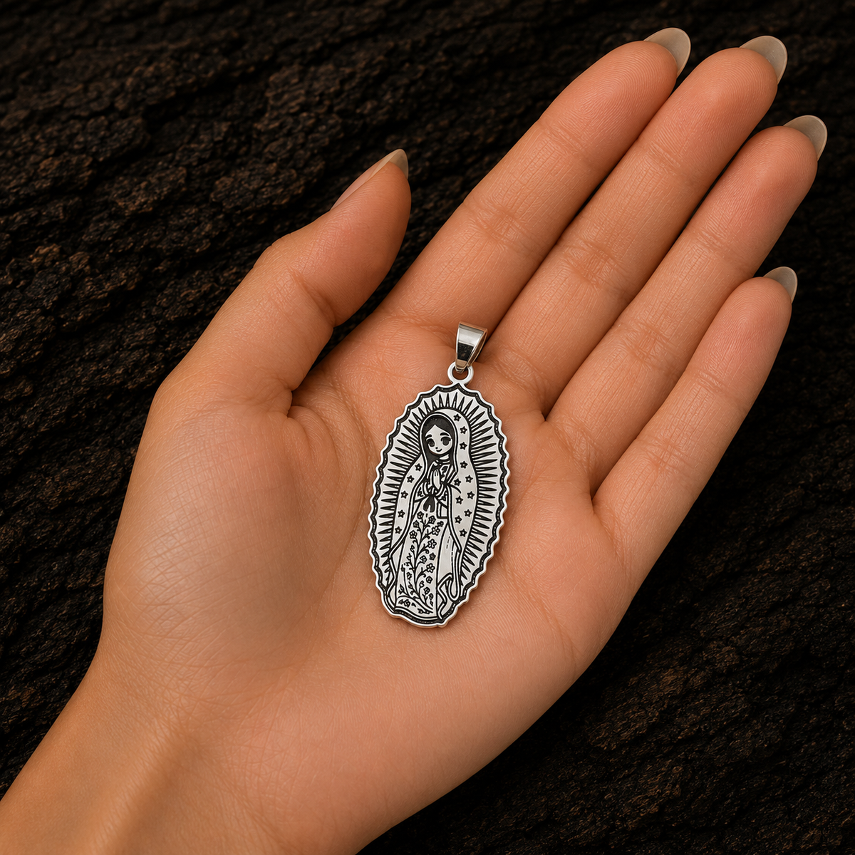 Our Lady of Guadalupe sterling silver pendant with detailed engraved artwork, displayed in a woman’s hand to show its size and craftsmanship.