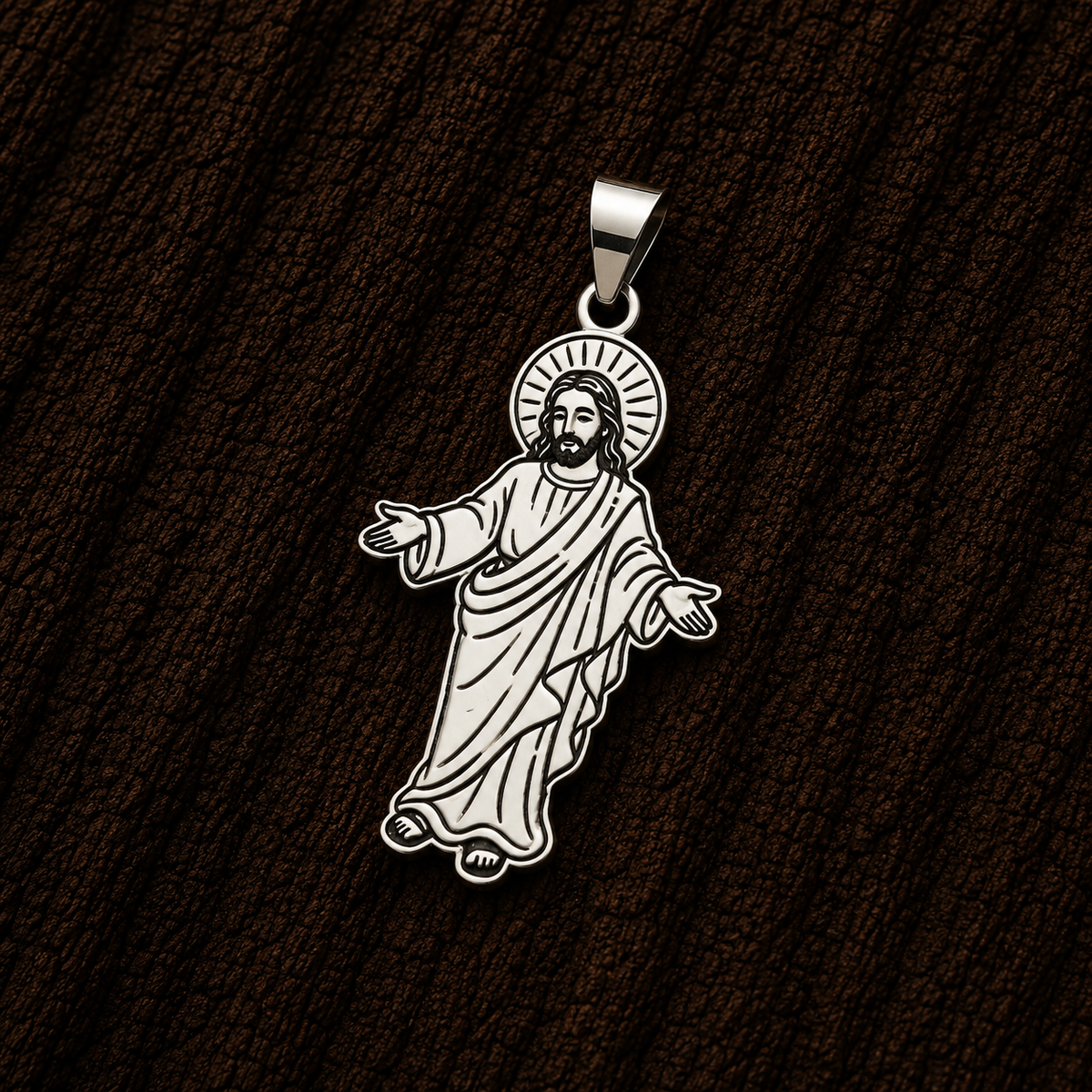 Jesus Christ sterling silver pendant with detailed religious artwork, displayed close-up against a dark wood background.