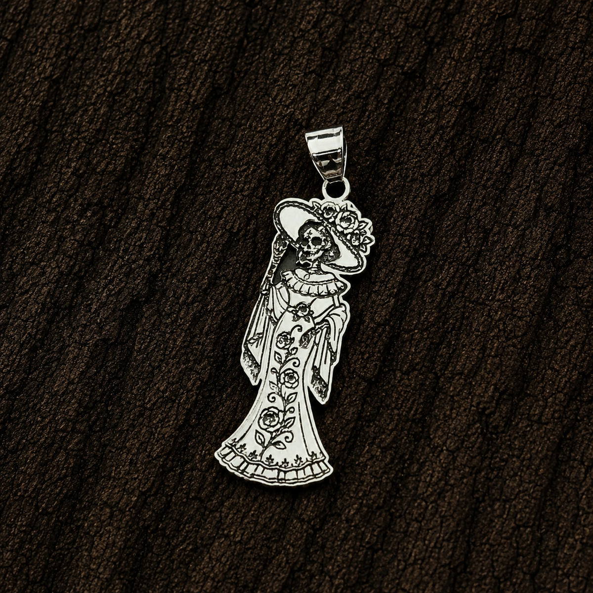 Catrina floral sterling silver pendant displayed close-up against a dark wood background.